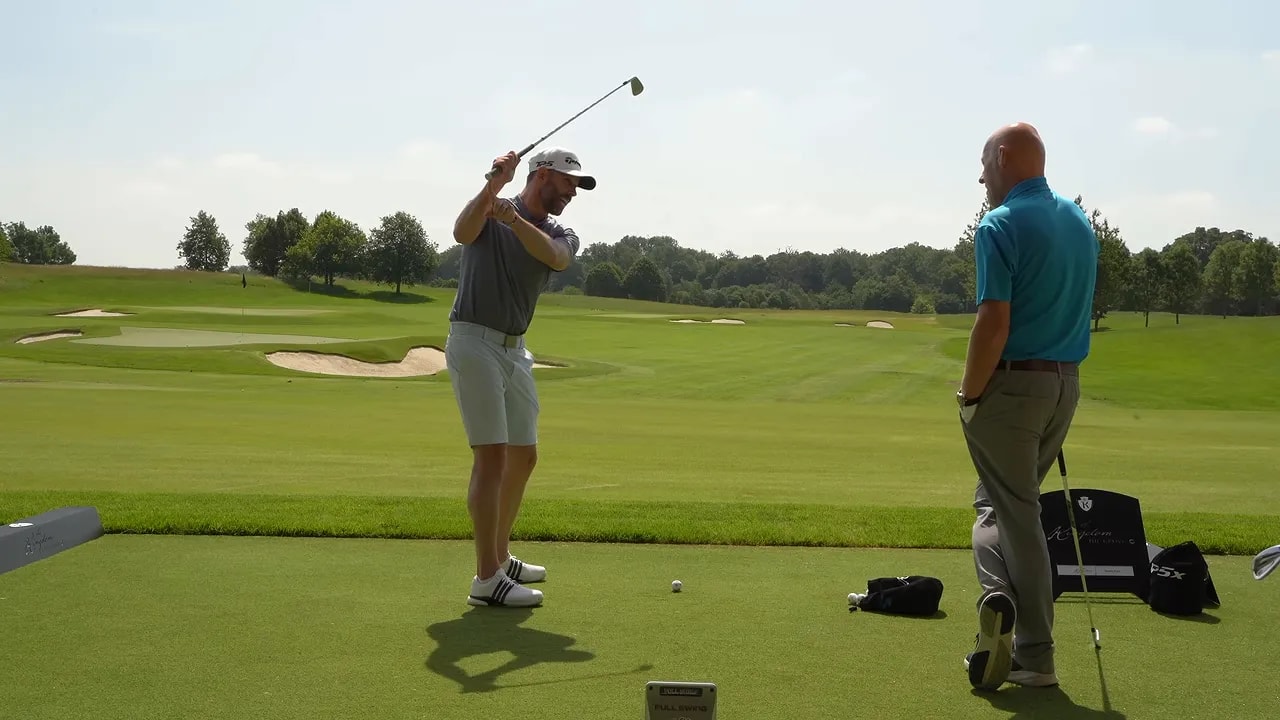 Golfer at the top of the backswing with an orange arc showing club movement