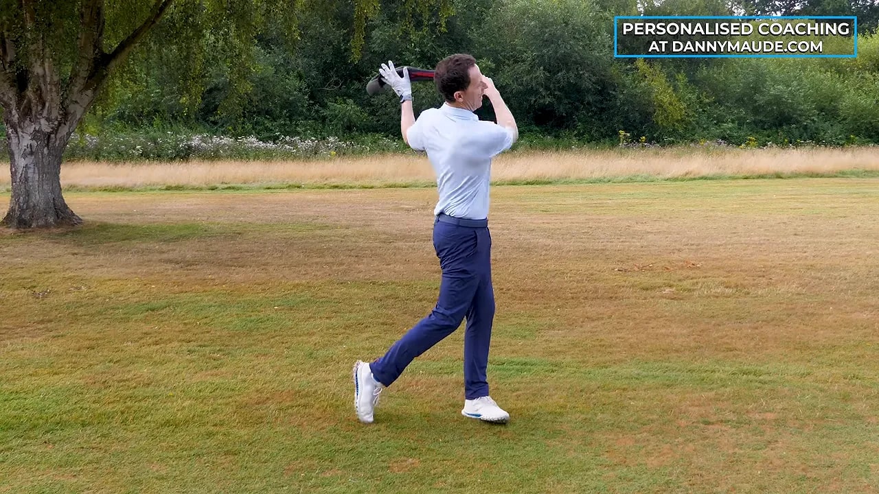 Golfer swinging a ball in a sock through the follow-through