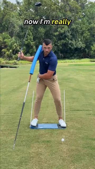Golfer at the top of the backswing with hip inside alignment stick and head near blue foam guide