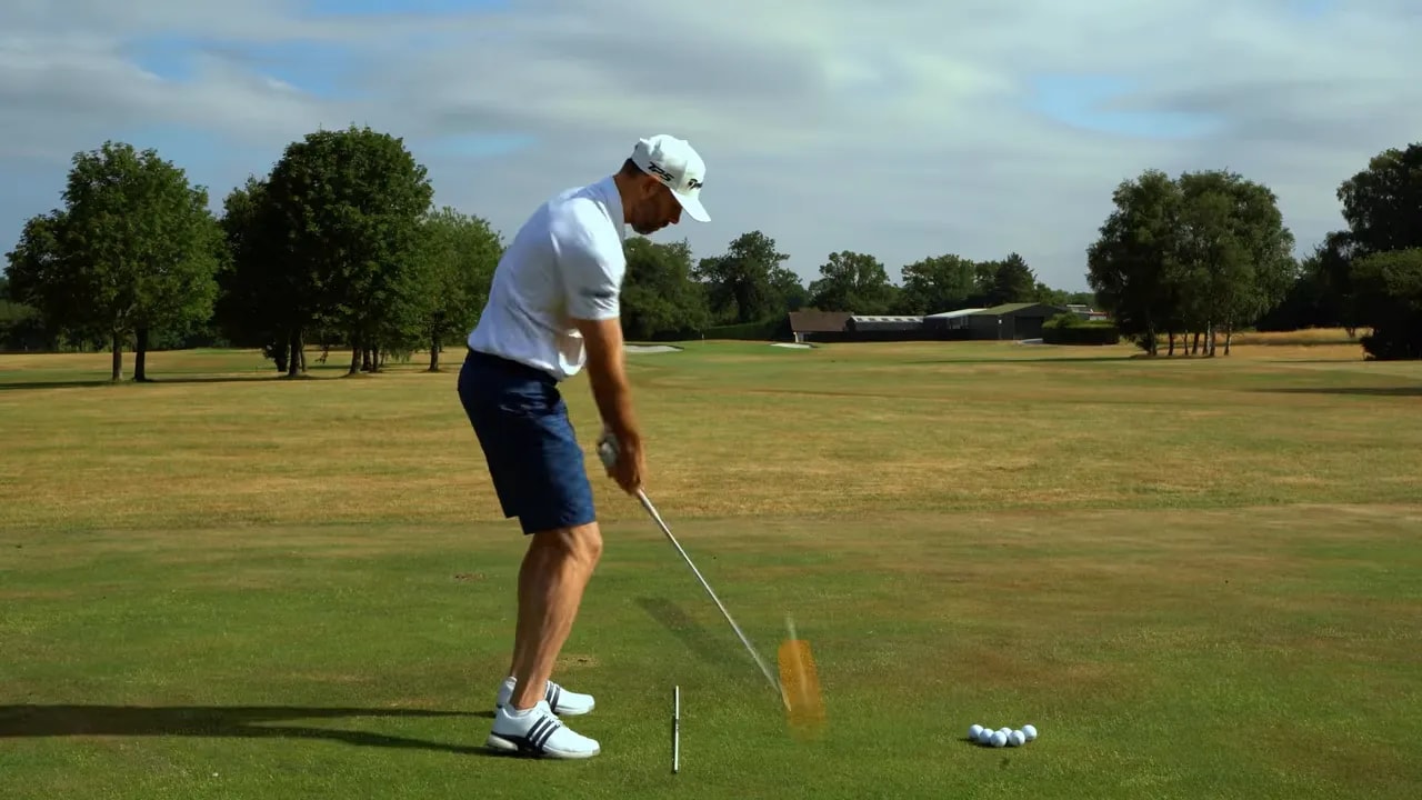 Golfer following through with an orange ball-flight arc rising to the right