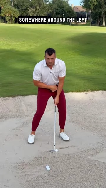 Golfer demonstrating shaft position toward the left thigh at bunker impact