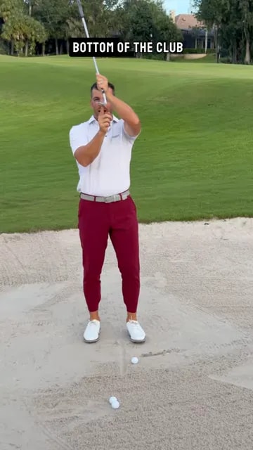 Golfer holding a wedge upright and pointing to the exposed bounce